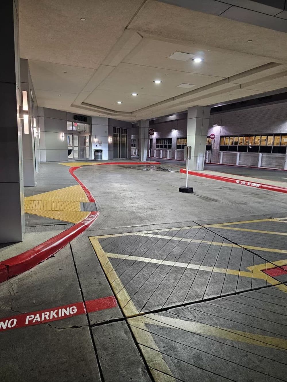 Empty parking garage with marked no parking areas and illuminated entrance during night.