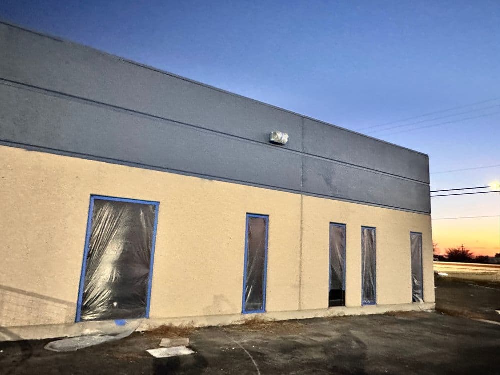 Exterior view of a commercial building at dusk with covered windows and blue trim.