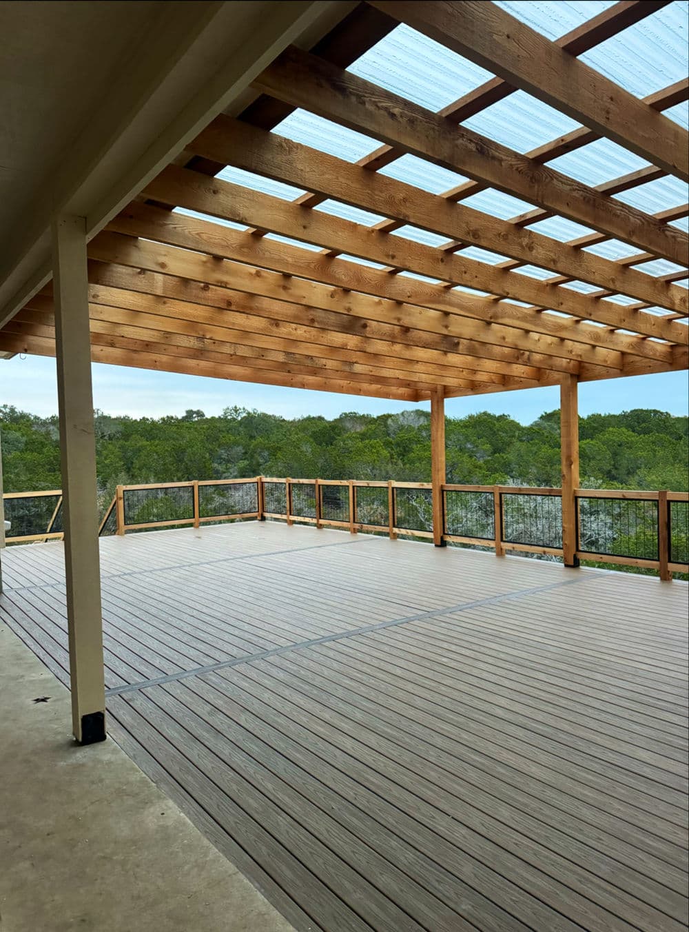 Spacious outdoor deck with wooden beams and scenic green views in the background.