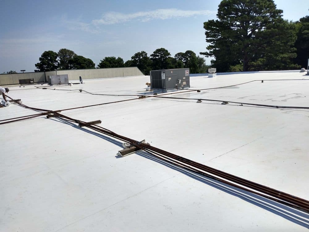 Roof view with HVAC units and utility lines under a clear blue sky.