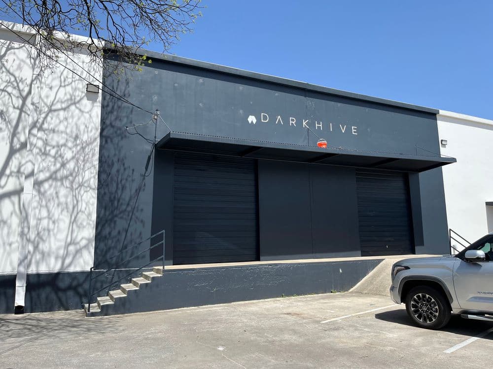 Exterior of DARKHIVE building with loading docks and a clear blue sky.