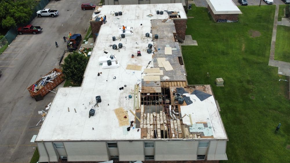 Roof renovation in progress, showcasing workers, materials, and equipment on a commercial building.