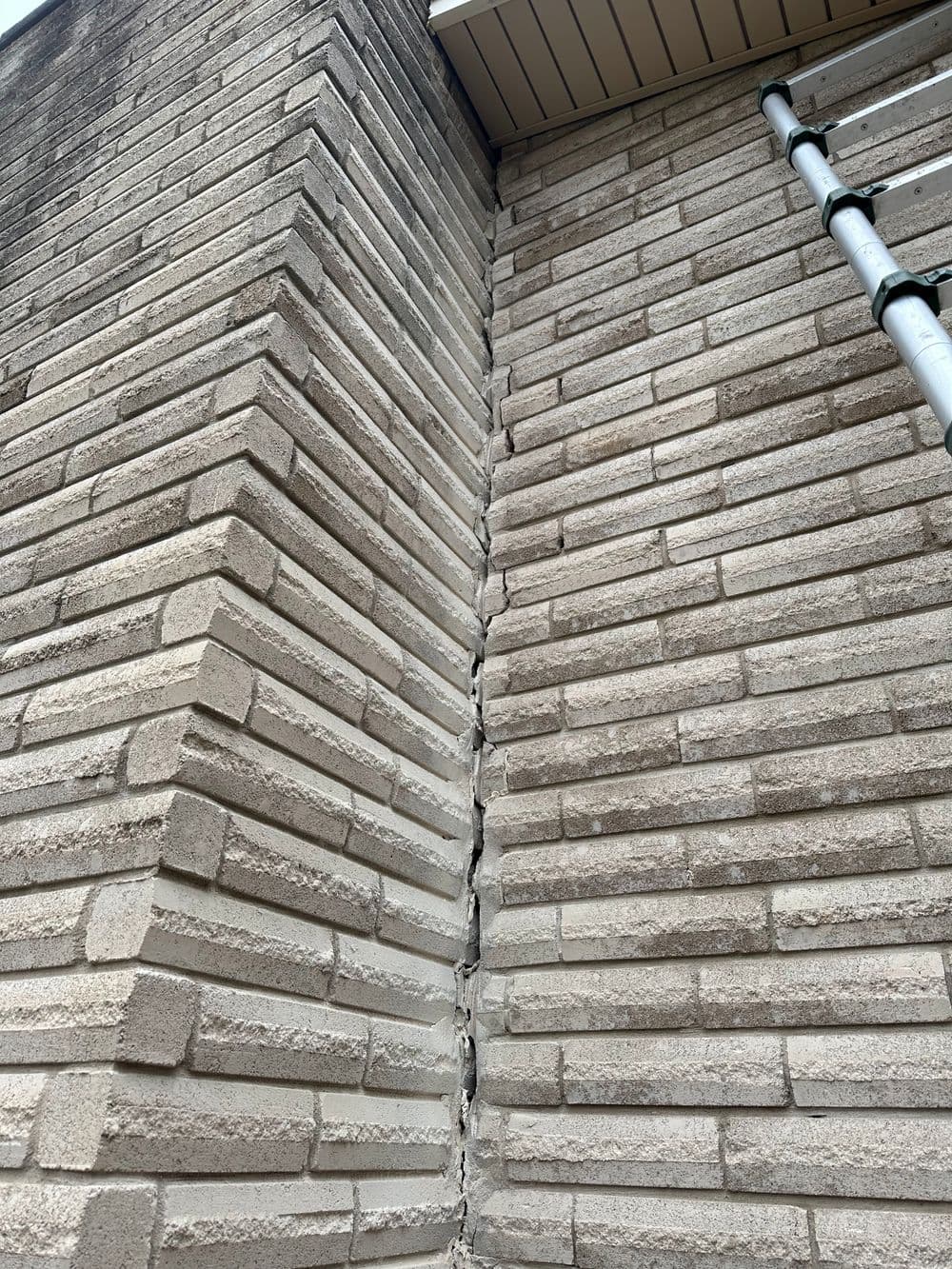 Cracked brick wall corner showing structural damage and potential repair needs.