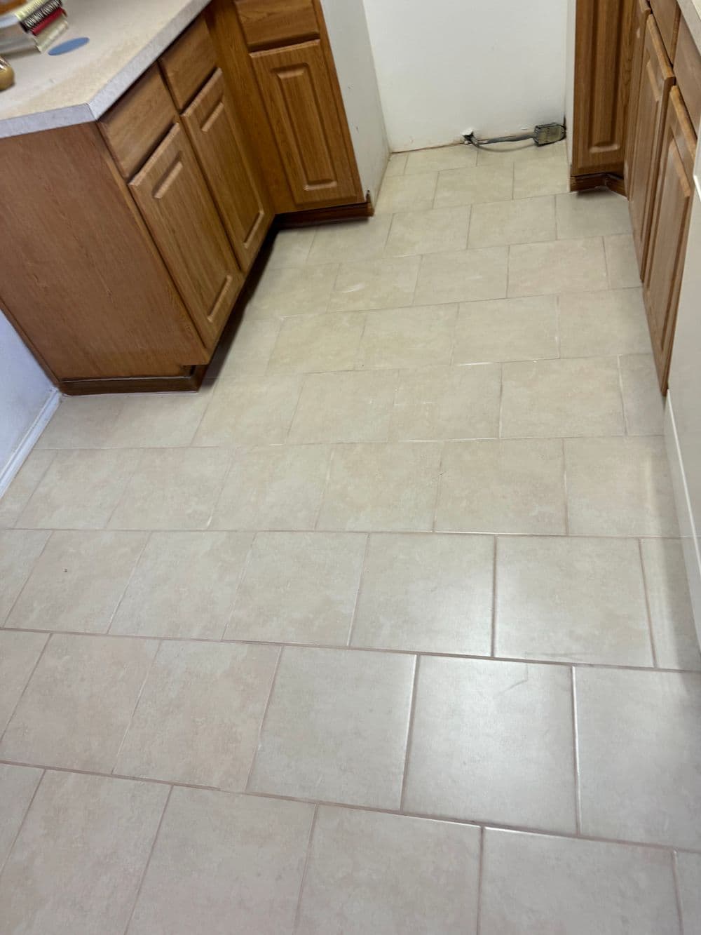 Clean, tiled kitchen floor with wooden cabinets and white walls.