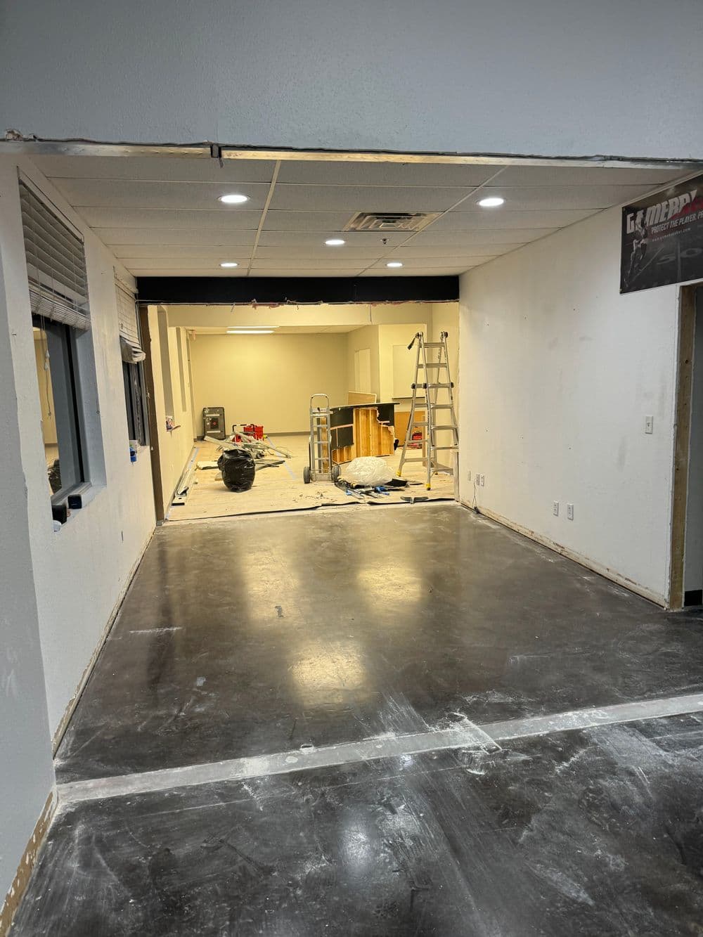 Renovated office space with exposed walls, ladder, tools, and polished concrete floor.
