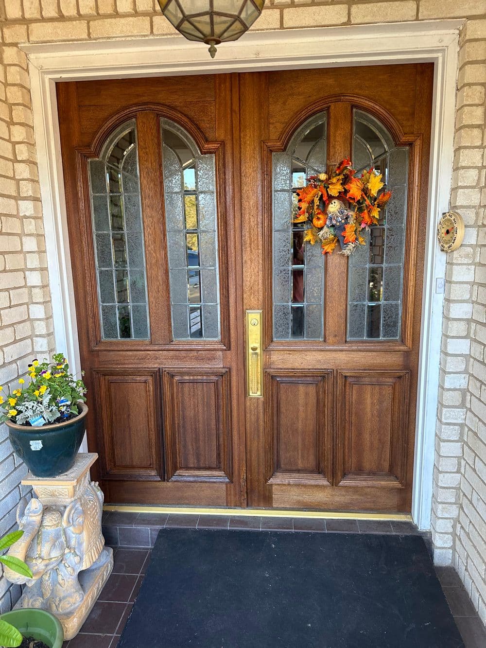 Welcoming wooden double doors adorned with an autumn wreath and potted flowers.