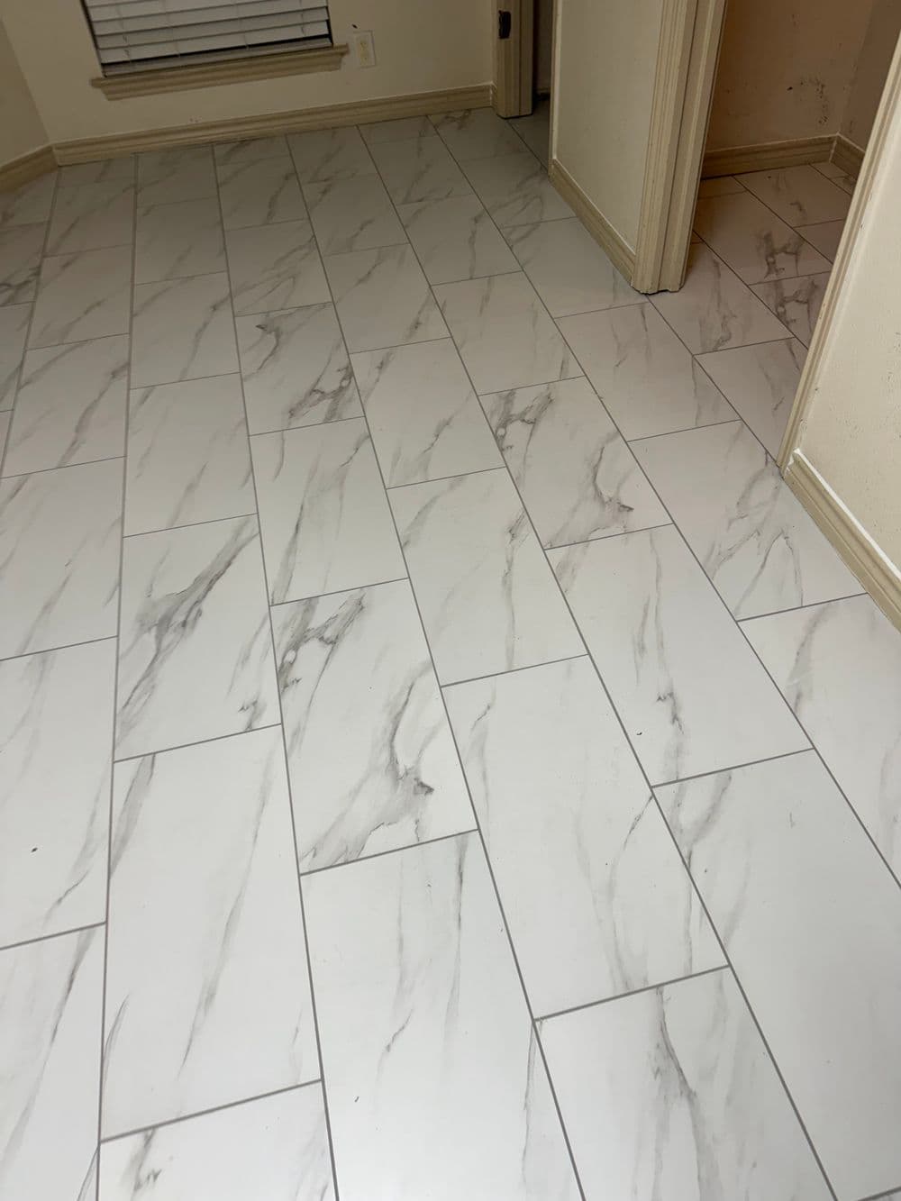Marble-patterned tile flooring in a room with beige walls and doorways.