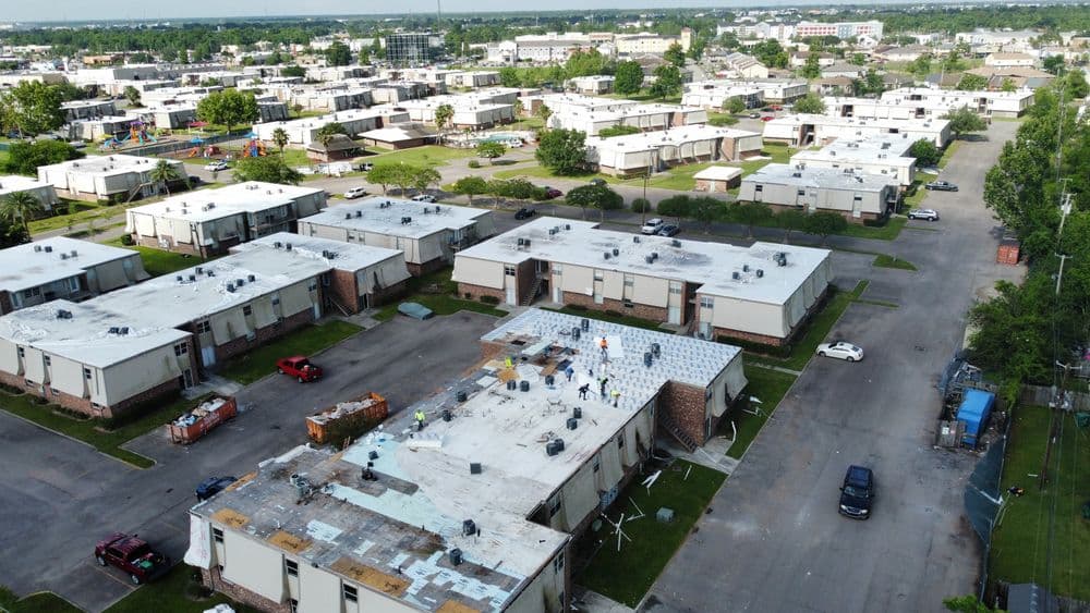 Aerial view of a residential area with buildings and workers on a roof.