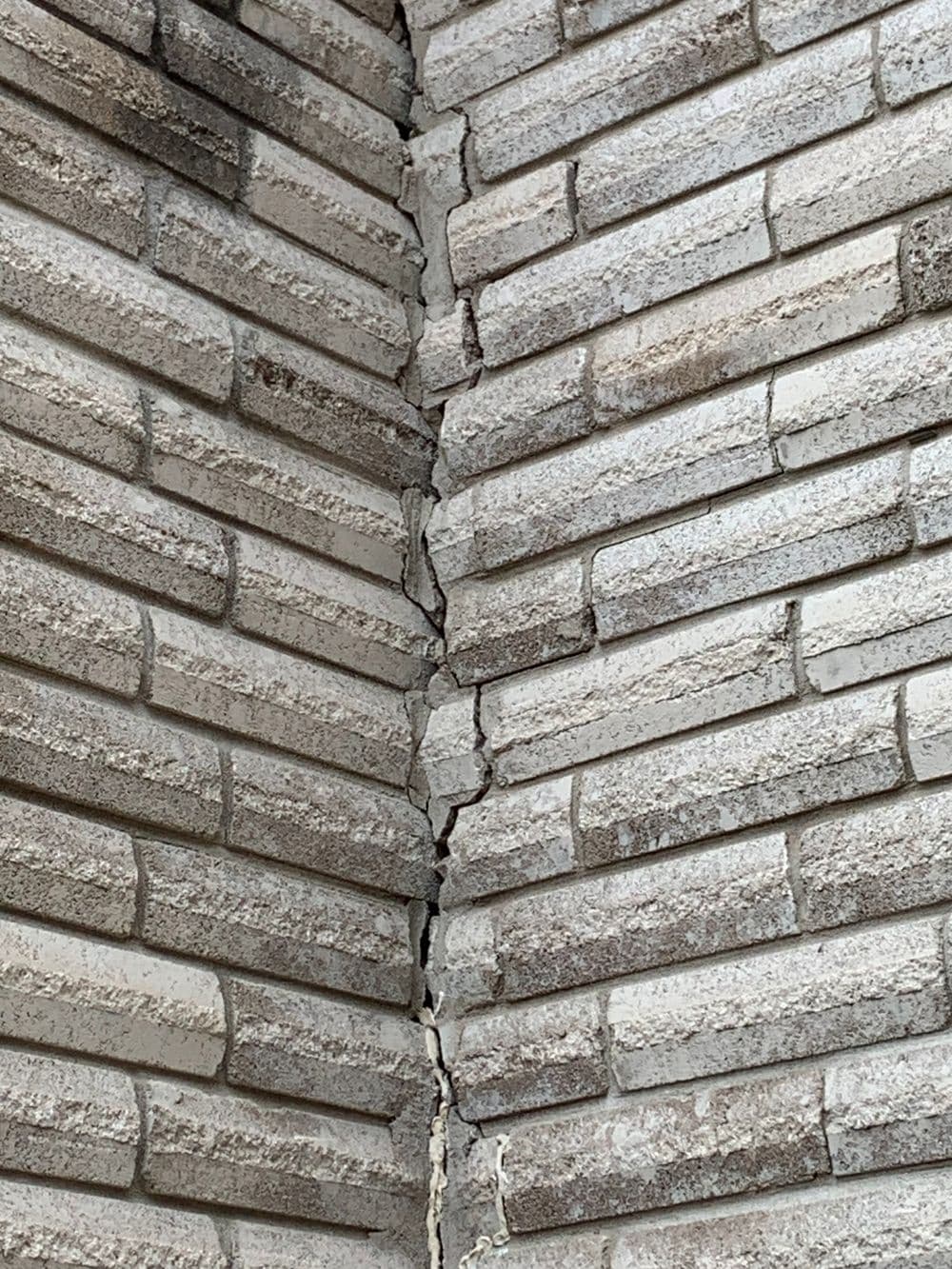 Cracked corner of a brick wall showing structural damage and wear.