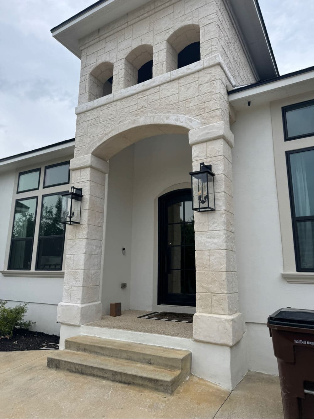 Elegant entrance of a modern home featuring stone archway and stylish lanterns.