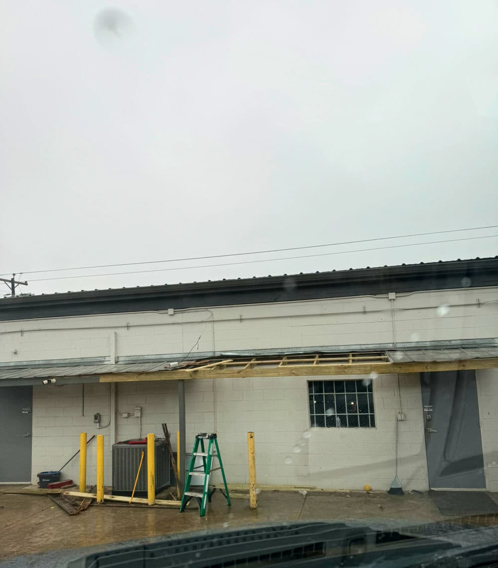 Ladder near a building under construction, partially covered roof, overcast sky.