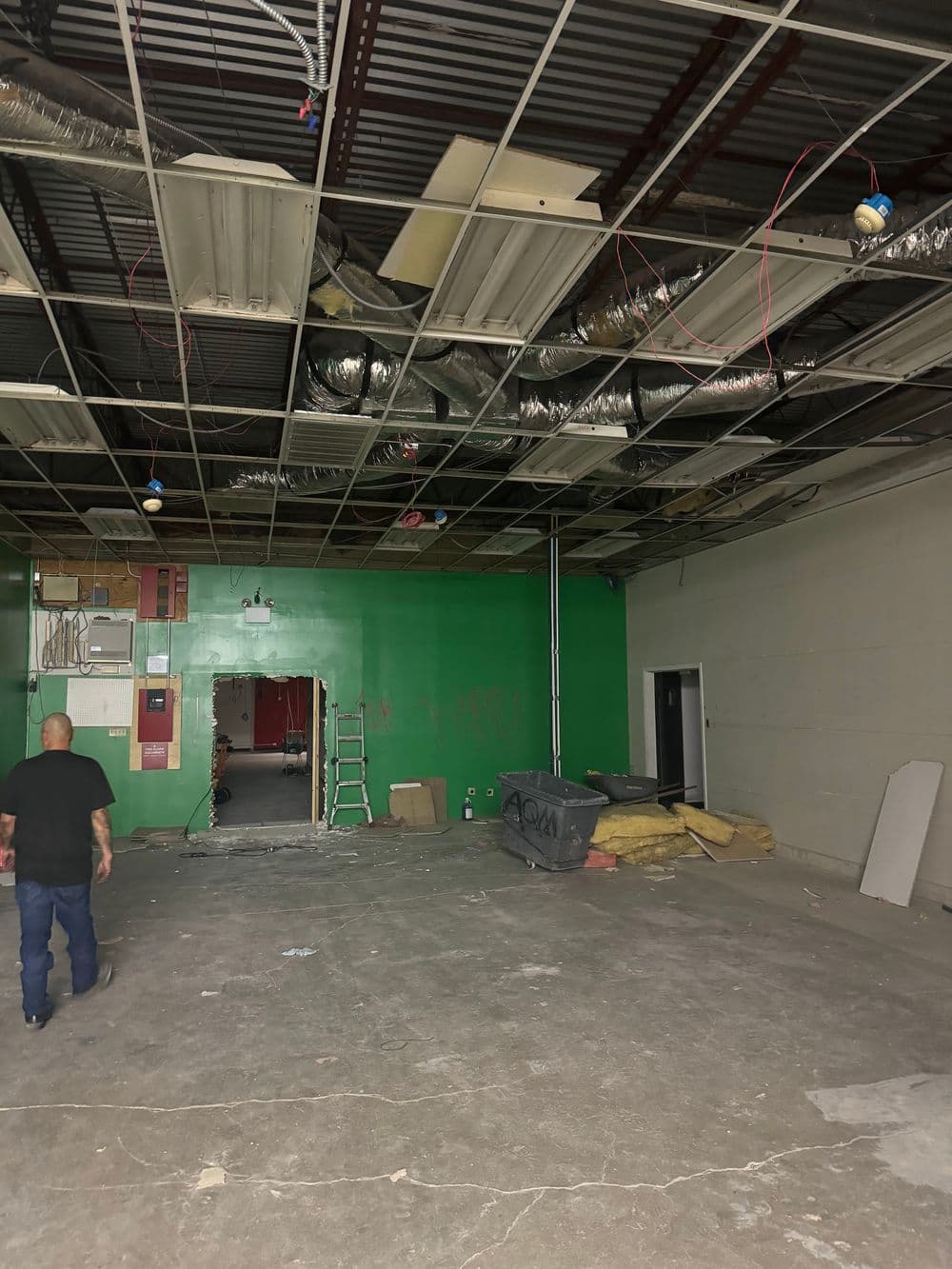 Renovation site showing green walls, exposed ceiling, and construction materials.
